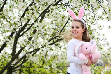 Uzun saçlı tavşan kulaklıklı çocuk gülümsüyor.