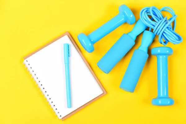 Notebook, pen and gym equipment top view on yellow background — Stock Photo, Image
