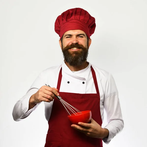 Cook with happy face in uniform uses whisk and bowl. — Stock Photo, Image