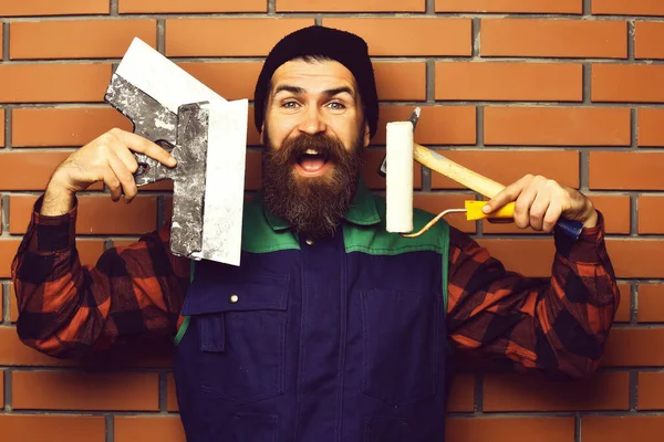 Бородатий художник тримає різні будівельні інструменти з щасливим обличчям — стокове фото