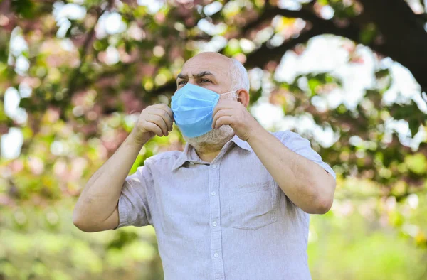 Środki bezpieczeństwa. Pandemia koronawirusa. Koncepcja pandemii. Powstrzymaj pandemię. Nie dotykaj twarzy. Wspieranie osób starszych podczas blokowania koronawirusów i dystansowania się od społeczeństwa. Starszy mężczyzna w masce. — Zdjęcie stockowe