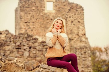 Güne burada başladığımız için şanslıyız. Kazaklı kız. Modaya uygun bir turist kız. Antik kentte sonbahar tatili. Seyahat yerleri. Kadın makyajı taş harabelerin üzerine oturur. Yüzyıl ortası şato kalıntılarını araştır