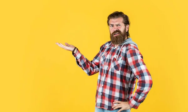 presenting product. confident and strict man in casual checkered shirt. mature bearded man in plaid shirt. handsome man wearing checkered shirt on yellow background. male beauty and fashion