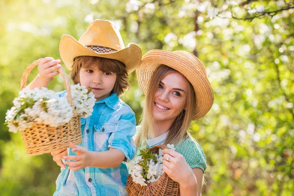 Moje słodkie dziecko. Szczęśliwego dnia rodzinnego. Matka i słodki syn w kapeluszach. Rodzinna farma. Spędzać razem czas. Piękna rodzina na świeżym powietrzu środowiska naturalnego. Rolnicy w kwitnącym ogrodzie. Koncepcja rancza. Kwiaty rosnące — Zdjęcie stockowe