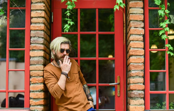 Cool mec relaxant. J'ai fait une pause-fumée. Hipster fumeur irlandaise pub arrière-plan d'entrée. L'habitude de fumer. Des lunettes de soleil brutales fumant du tabac. Fumer à l'extérieur. Homme mature à la mode avec cigarette — Photo