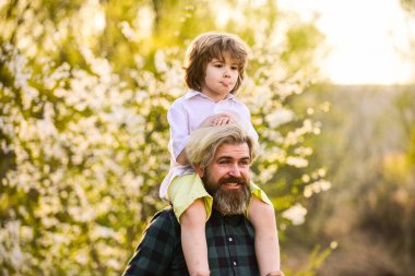 Seni görmek ne güzel. Bahar zamanı birlikte. Küçük çocuk babasıyla mutlu. Aile eğleniyor. Parkta çiçek açıyor. çocukluk ve ebeveynlik mutluluğu. Sevgi ve destek. Baba ve oğul çiçek açan ağaçta