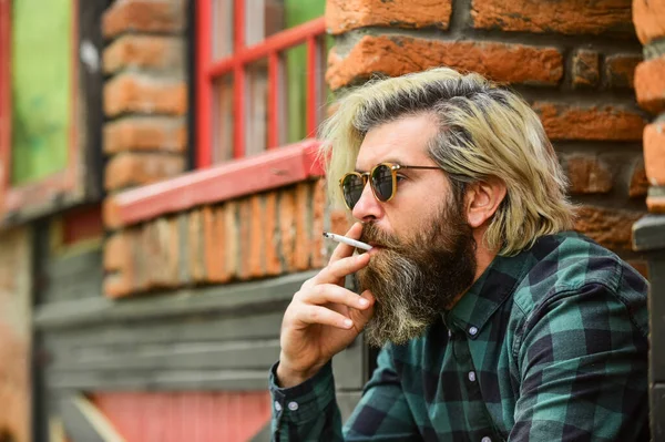 Brutal caucasien mâle dans des lunettes. Homme fumant en plein air. Homme mature à la mode fumant de la cigarette. L'homme hipster fumant. Fumer et l'habitude. fumée secondaire ou fumée passive. espace de copie — Photo