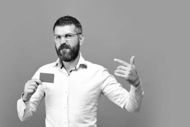 Beyaz gömlekli siyah sakallı adam kartvizit tutuyor.