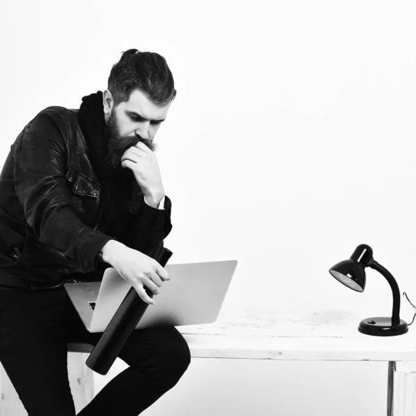 Barbudo brutal caucásico hipster sentado en la mesa con el ordenador portátil — Foto de Stock