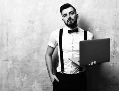 Sakallı ve kendine güveni olan menajer elinde dizüstü bilgisayar tutuyor.