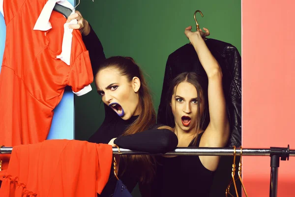 Twee boze mooie meisjes schreeuwen naar kleding rek — Stockfoto
