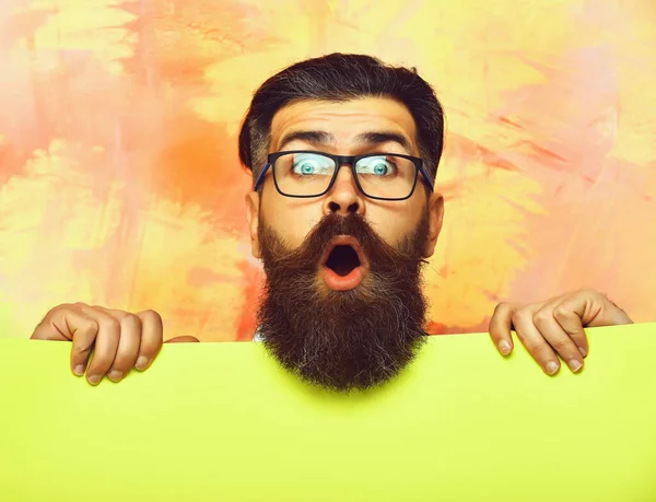 Hombre barbudo con cara sorprendida en gafas sobre fondo colorido — Foto de Stock