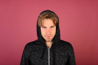 Koyu pembe arka planda, sarı saçlı bir adam.