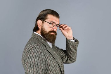 Hırslı bir manken. Gri arka planda duran yakışıklı adam. Ciddi sakallı iş adamı. Modern görünümlü şık, olgun bir adam. Erkek ceketi dolabı. Şık bir adam gözlük takıyor.