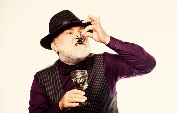 Add spider cocktail recipe. Weird old grandfather with gray beard eating spider. Disgusting Halloween drink. Exotic food. Halloween party. Elegant bartender wear hat and vest. Halloween concept — Stock Photo, Image