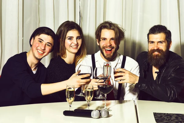 Felices amigos sonriendo y tintineando vasos con diferentes bebidas alcohólicas — Foto de Stock
