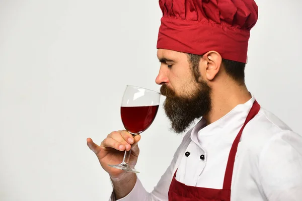 Cook med allvarligt ansikte i vinröd uniform drycker alkohol. — Stockfoto