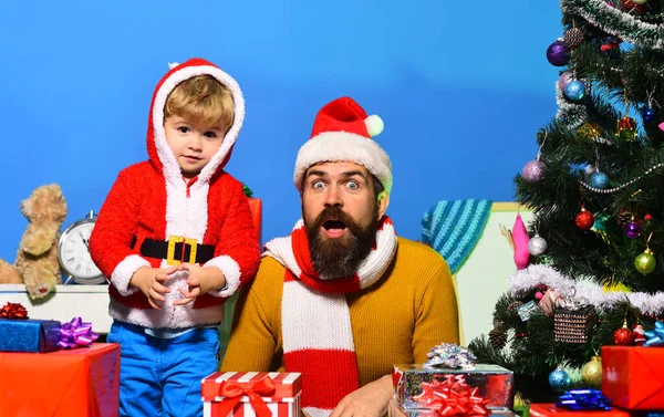 Weihnachtsmann und kleiner Helfer inmitten von Geschenkboxen am Weihnachtsbaum — Stockfoto