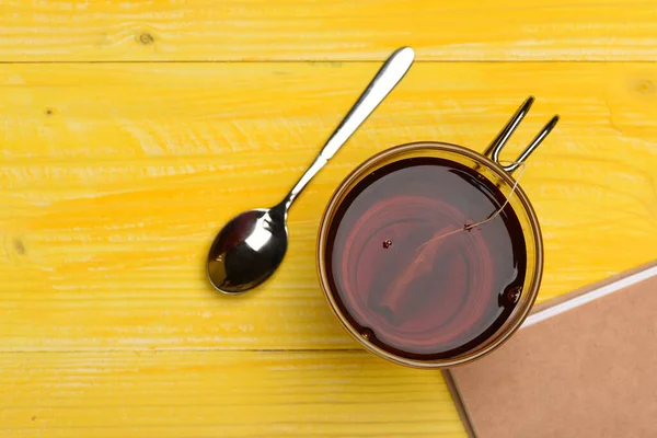 Glas schwarzer Tee mit Teebeutel neben geschlossenem Buch — Stockfoto