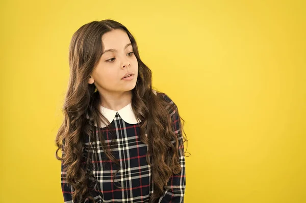 Pure beauty. Small beauty long curly hair. stylish school uniform for kids. beauty of healthy hair. copy space. little fashion model yellow background. her hair is perfect. happy childrens day — Stock Photo, Image