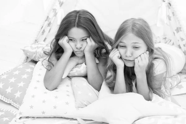 Bored kids on quarantine. Sisters best friends spend time together lay on pillows. Girls feeling sad. Girlish leisure. Sisters share gossips at home. Bored children. Boring activity. Tired and sleepy