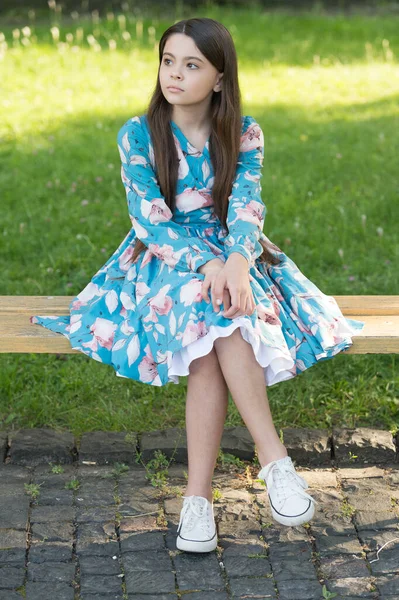 Menina com cabelos longos relaxante no parque ensolarado dia verde grama fundo, à espera de alguém conceito — Fotografia de Stock