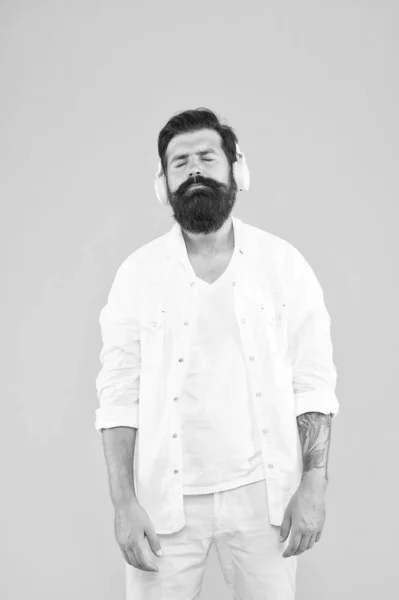 Plaisir audio. Son parfait. Hipster écouter de la musique casque stéréo. Casque sans fil moderne. Musique électronique et pistes house. Musique instrumentale. Homme barbu casque fond jaune — Photo