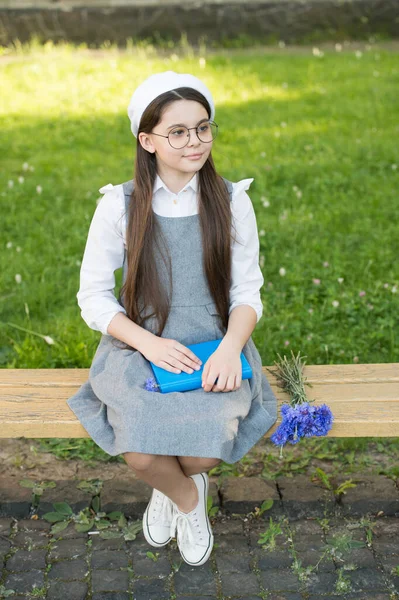 Elegante colegiala niña con libro en el parque, concepto de tarea — Foto de Stock