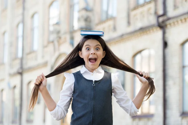 Nejsi sám s knihou. Happy kid hold book on head outdoors. Malý knihomol nosí dlouhé vlasy. Školní knihovna. Čtení literatury. Formální vzdělání. Každá přečtená kniha vám přidá do mozku novou poličku — Stock fotografie