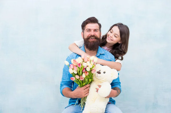 Pai, o meu coração pertence-te. Pequena filha abraçar o pai. A família feliz celebra o dia de pais. Criança pequena e homem barbudo segurar brinquedo e flores. Paternidade e laços paternos. Dia feliz dos pais — Fotografia de Stock