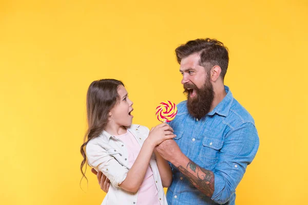 Gelukkig familie vader en dochter eten lolly geel achtergrond, grappig strijd concept — Stockfoto