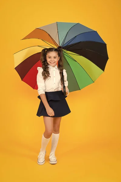 Girl with umbrella. Rainy day walks. Happy childhood. School time. Rainbow style. Colorful life. Schoolgirl happy with umbrella. Fall weather forecast. Fashion accessory. Umbrella protective shield