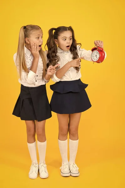 De laatkomer zal gestraft worden. Het is tijd. Schoolrooster. School tijd. Schoolmeisjes en wekker. Kinderen scholieren. Kennisdag. Verrast verrast schokkende kinderen houden wekker tellen tijd — Stockfoto