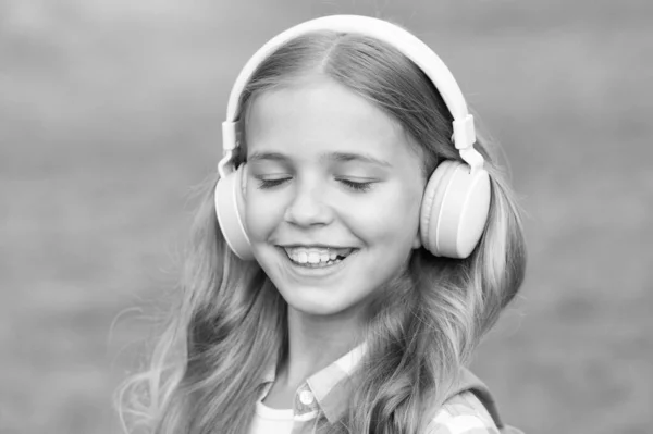 Poslouchejte hudbu při chůzi. Holčičí sluchátka poslouchají hudbu. Vzdělávací podcast. Holčička má ráda hudbu. Příjemné chvíle. Dětská sluchátka poslouchají hudbu. Koncept audioknihy. Studium audio lekcí — Stock fotografie