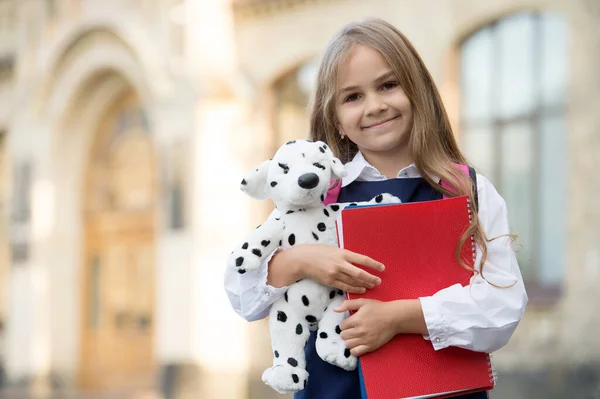 Ucz się i graj. Szczęśliwe dziecko trzymać psa zabawki i książki. Wracać do szkoły. Szkoła podstawowa. Kreatywność i wyobraźnia. Przedszkole i żłobek. Po szkole i przedszkolu. Świetne miejsce do nauki, kopiowanie przestrzeni — Zdjęcie stockowe