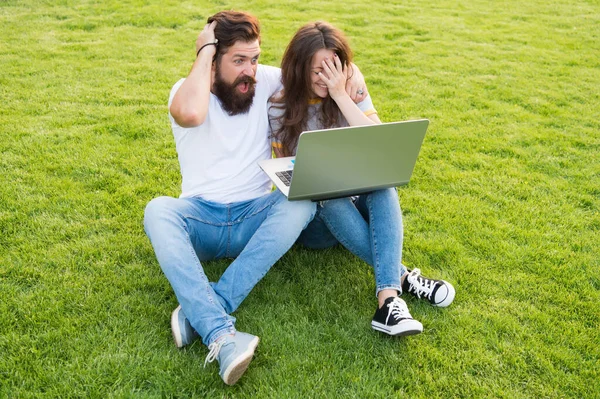Glada par använder laptop sitta grönt gräs, chockerande koncent koncept — Stockfoto
