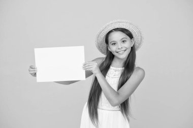 Çocuk gezgin konsepti. Yaz alışveriş satışları. Mutlu küçük kız boş kağıt tutuyor. kopyalama alanı. Sıcak tatil zamanı. Ilık ülkelere seyahat. Çocuk bahar modası. Hasır şapkalı kız. reklam