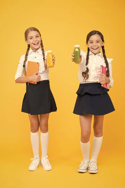 Healthy food. diary and dairy. lunch time. small girls with book. read and write. happy girls study with notepad. literature lesson. back to school. Pupils drink juice at library. childrens health — Stock Photo, Image