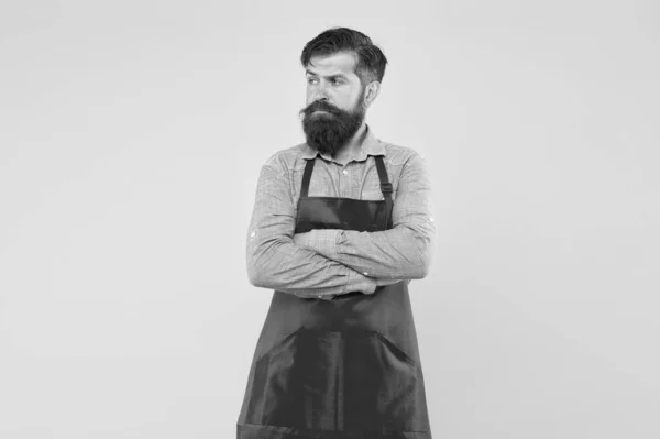 Professioneel koken. Zijn nieuwe bedrijf. Een man in winkelassistent uniform. serieuze man met rood schort op gele achtergrond. Zelfverzekerde uitdrukking. Knappe mannelijke barista werkt. volwassen barman — Stockfoto