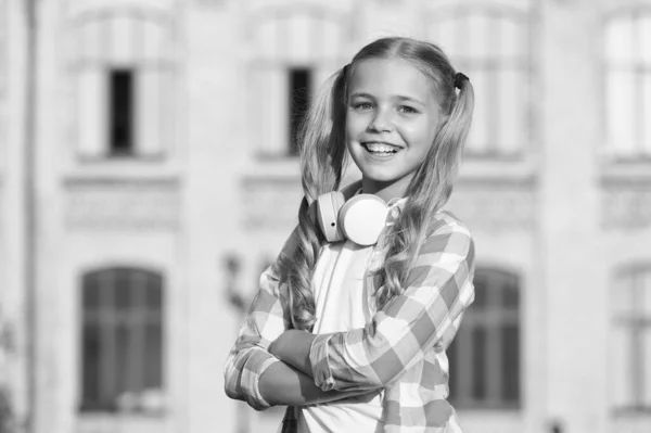 Kind mit Kopfhörer. Kinderglück. fröhliches Kind in verspielter Stimmung hat blonde Haare. niedlich und stylisch Frisur. Freizeit im Frühling. inspiriert von Lieblingssong. kleines Mädchen hört Musik — Stockfoto