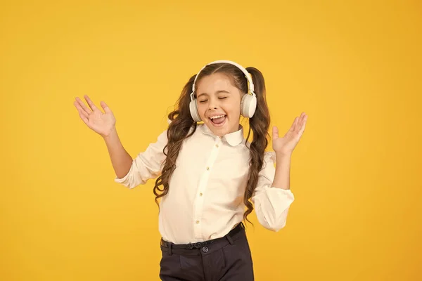 La canción hace clic con su estado de ánimo. Adorable niñita cantando una canción sobre fondo amarillo. Lindo niño pequeño escuchando la canción jugando en los auriculares. Disfrutando de su canción favorita — Foto de Stock