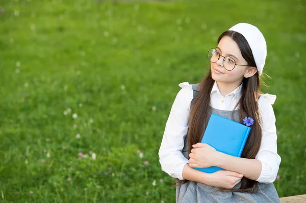 Elegant schoolgirl child girl reading book in park, poetry writer concept