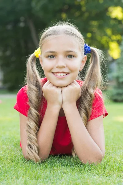 緑の芝生でリラックスした女の子かわいいポニーテールの髪型、サマーキャンプのコンセプト — ストック写真