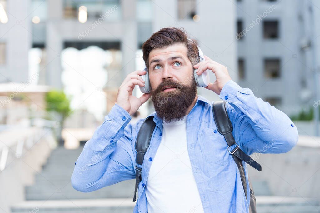 We have our ears in the streets. Bearded man wear ear phones outdoors. Hipster listen to music in headphones. Comfortable ear pads. Hearing protection. Modern life. Ear knowledge for your soul