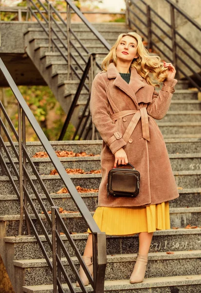 Девушка тёплое пальто стоять на заднем плане городской лестнице. Создайте осенний наряд, чтобы чувствовать себя комфортно и красиво. Осенний наряд. Женщина носить стильный наряд и носить сумочку. Одежда из современного теплого и стильного экомеха — стоковое фото