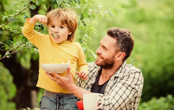 Let me help you. family rest time. happy fathers day. Little boy with dad eat cereal. Morning breakfast. Tasty food. healthy food and dieting. Dairy products. son and father eating outdoor — Stock Photo, Image