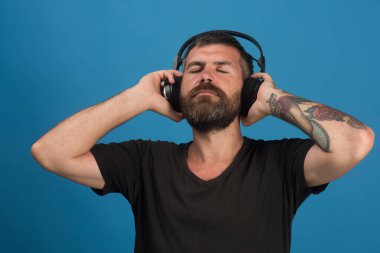 Adamın kulaklığı mavi arka planda. Zevk, müzik ve yaşam tarzı