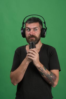 Adam mikrofonu yeşil arka planda tutuyor. Teknoloji ve müzik konsepti.