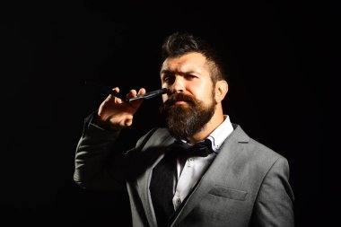 Uzun sakallı adam jileti gözüne yakın tutuyor.