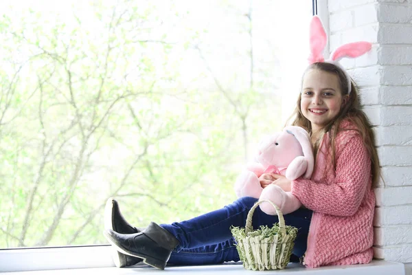 Paskalya tatili, küçük çocuk sarılma tavşanı. Oyuncağı olan küçük bir kız. Pencereye poz veren sepetli çocuk.